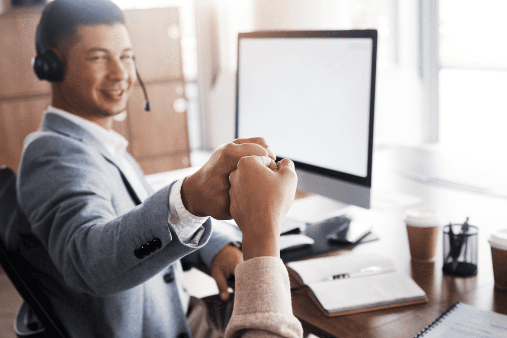 A professional and another person fist-bump at their desk