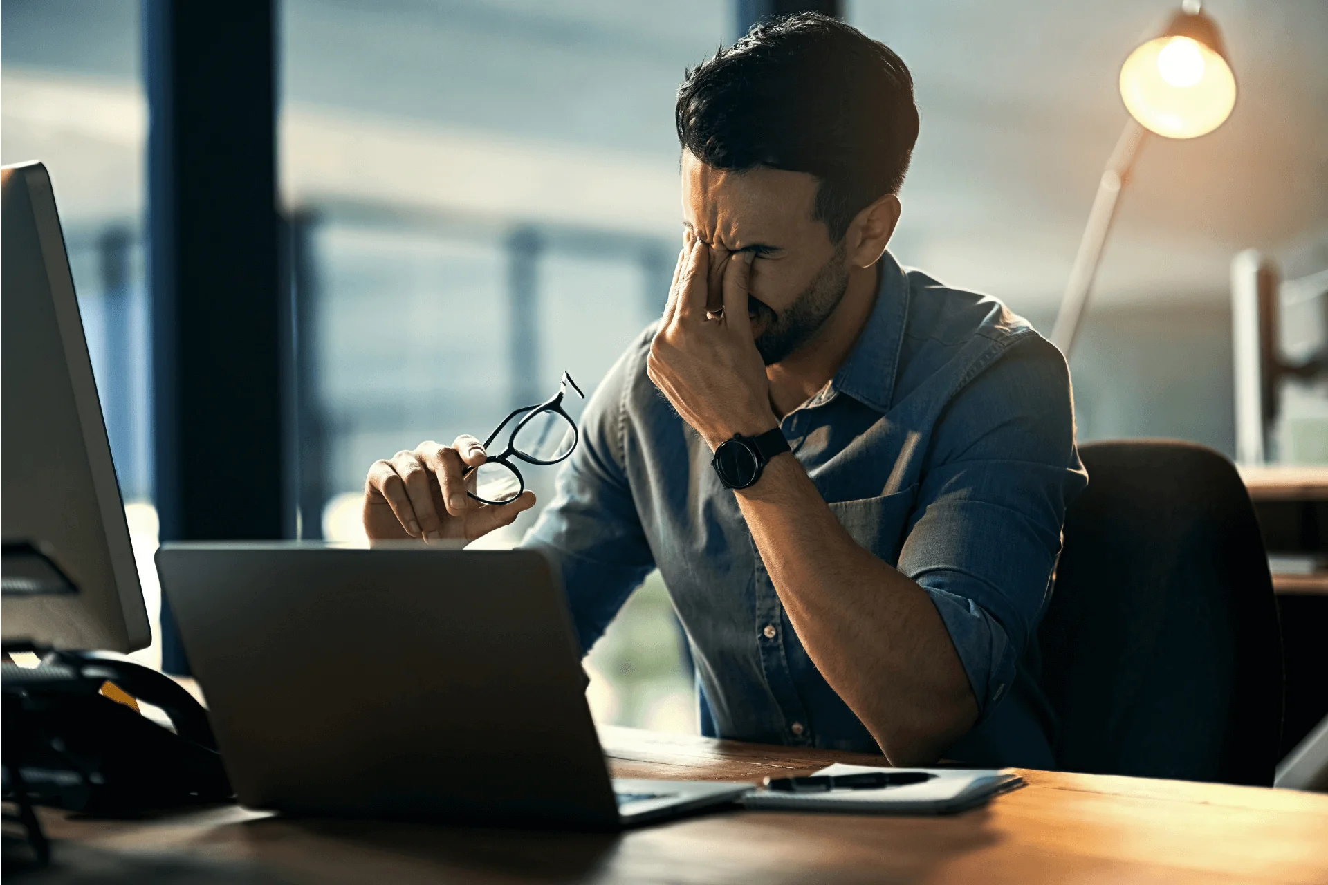 a person sitting at a desk in an office with their eyes closed in frustration
