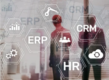A group of people standing in front of a glass wall with the words ERP, CRM, and HR on it